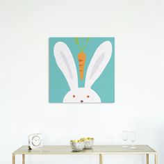 a painting of a rabbit with a carrot on it's head is hanging above a table