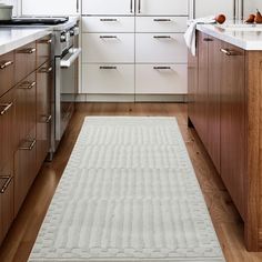 a white rug in a kitchen with wooden cabinets and drawers on either side of the door