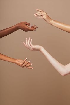 four hands reaching out towards each other with their fingers in the air, against a beige background