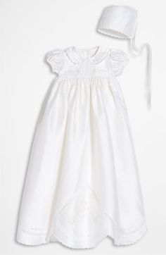 a white dress and hat are on display in this image, it looks like an infant's christ gown