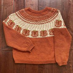 an orange and white sweater sitting on top of a wooden floor