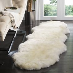 a large white sheepskin rug on the floor in front of a couch and chair