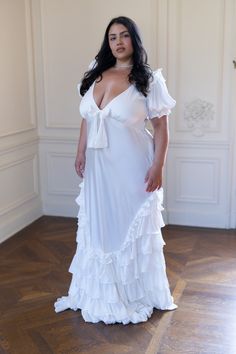 This exquisite 1920’s style wedding slip dress is perfect for your bridal ceremony look or as a stunning pre-wedding dress. Crafted from luxurious silk charmeuse, the bias-cut silhouette and pleated ruffles skim over your curves, creating a flattering fit worthy of Gatsby's lavish soirées. The bodice features delicate flutter cap sleeves and a sweetheart neckline adorned with a charming bow detail. Silk charmeuse bias cut slip dress with flutter cap sleeves Layers of pleated ruffles on the skirt Womens Plus Size Dresses For Wedding Guest, Plus Size Backless Dress, Wedding Night Satin Dress With Ruffles, Reception Dress Plus Size, Plus Size Elopement Dress, Wedding Slip Dress, Bell Sleeve Wedding Dress, Slip Wedding Dress, Skirt Bow