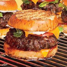 hamburgers with cheese and lettuce sitting on a grill