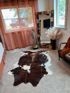 a living room with a cow hide rug on the floor next to a chair and mirror