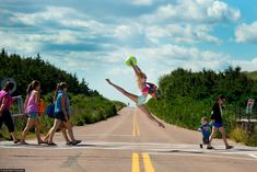 a girl is jumping in the air with a frisbee while people walk by