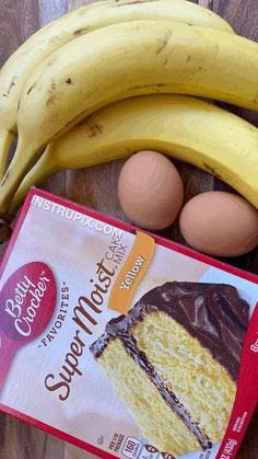 some bananas and cake sitting on a table next to an egg in a carton