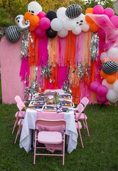 a table set up for a party with balloons and streamers