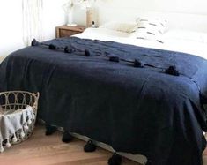 a bed with black bedspread and pom poms on it