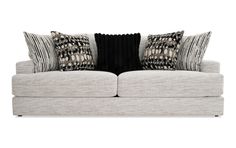 a white couch with black and grey pillows on top of it's back end