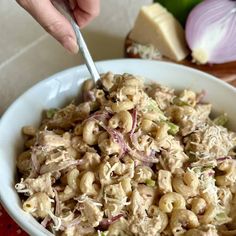 a bowl filled with macaroni salad next to sliced onions