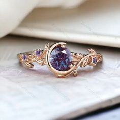 a ring with an oval shaped purple stone surrounded by leaves