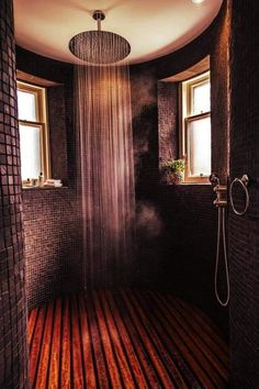 a shower head in the middle of a room with wooden floors and windows on both sides