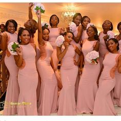 a group of women standing next to each other in pink dresses and holding bouquets