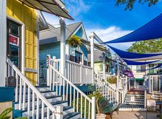 several houses with blue and yellow awnings on the front porch, stairs leading up to them