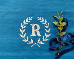 the letter r is placed next to a blue ribbon and a plant with leaves on it