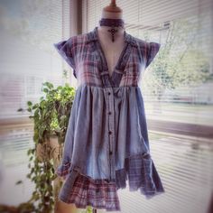 a dress is hanging on a mannequin in front of a window with a potted plant