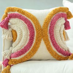 a decorative pillow with tassels and fringe on a white couch cushion in a living room