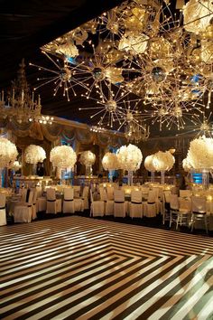 a banquet hall with tables, chairs and chandeliers