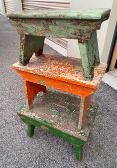 an old green wooden bench sitting on top of a gray carpeted floor next to a building