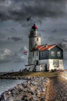 a lighthouse on top of a hill next to the ocean