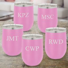 four pink wine glasses with silver rims and monogrammed letters on them sitting on a wooden table