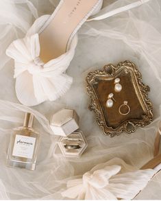 an assortment of wedding accessories including shoes, ring boxes and perfume bottles on a white background