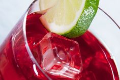 a close up of a drink in a glass with a lime slice on the rim