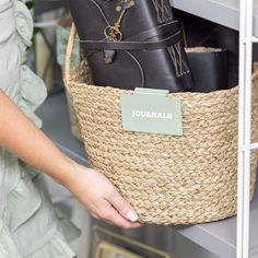 a woman is holding a basket full of black purses in her hand and the label on it says journal