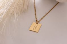 Introducing our stunning 18K Gold Filled Initial Letter Necklace, a personalized accessory that exudes style and individuality. This exquisite necklace features a captivating Old English font, adding a touch of vintage charm to your look. Crafted with meticulous attention to detail, each letter pendant is made from high-quality stainless steel and meticulously filled with a lustrous 18K gold finish. This ensures a lasting and radiant piece of jewelry that withstands the test of time, maintaining its brilliance for years to come. The square pendant design gives a modern twist to the classic initial necklace, making it a versatile and fashionable choice. The pendant measures [insert dimensions here], providing a statement-making size that beautifully showcases your chosen initial. With a ran Square Pendant Initial Necklace Gift, Tarnish Resistant Square Pendant Initial Necklace For Gift, Personalized Initials Necklace With Square Pendant, Engraved Initial Necklace With Square Pendant As Gift, Square Pendant Necklace With Initials For Personalized Gift, Luxury Personalized Initial Pendant Necklace, Engraved Square Pendant Initial Necklace For Gift, Luxury Personalized Pendant Charm Necklaces, Luxury Initial Pendant Name Necklace As Gift