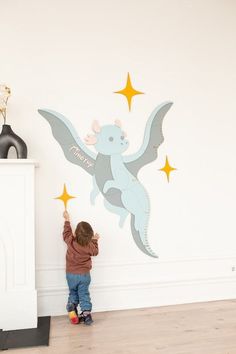 a little boy standing in front of a wall with an angel decal on it