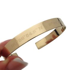 The Coordinates Cuff Bracelet is a timeless expression of love, perfect as a long-distance gift. Crafted with care, this exquisite piece is made of 14K Gold filled, radiating both elegance and durability.  Its meticulously hand-polished surface lends a luxurious gleam to the wrist. Designed for both aesthetic allure and personal sentiment, the bracelet offers an adjustable size to ensure a comfortable fit.  A truly personalized gift for her, it's available for two sides to be engraved with the coordinates of a cherished location and personalized mesage , allowing you to encapsulate memories of a special place.  What sets this bracelet apart is the option for a custom hidden message inside, an intimate touch that turns this accessory into a treasure of affection. Whether celebrating an anni Engraved Cuff, Distance Gifts, Long Distance Gifts, Gold Armband, Personalized Bracelet, Gold Bracelet Cuff, Gold Cuffs, Elegant Bracelet, Personalized Bracelets