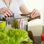 a woman is cooking in the kitchen with her hands on the pot and green vegetables