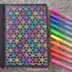 a notebook with crayons next to it and some pens on the floor in front of it