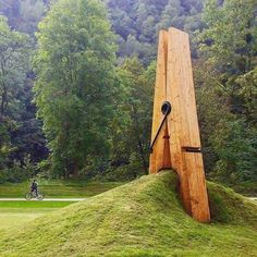 a large wooden sculpture in the middle of a field with a bicycle parked next to it