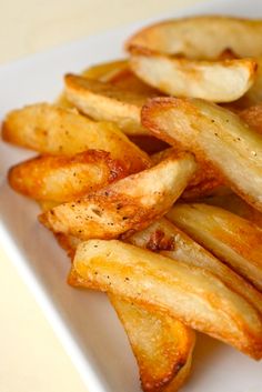 some french fries on a white plate with seasoning sprinkled around the edges