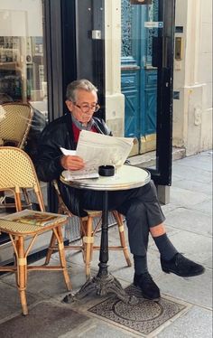 a man sitting at a table reading a newspaper