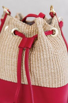 Crafted from raffia and leather, this chic bucket bag brings a touch of summer style to everday looks. Raffia body with leather trims 2 interchangeable/removable leather straps: shoulder length and crossbody Leather drawstring cinch closure Canvas lining with interior zip pocket Leather base Dimensions Approx. 8.5" H, 8" W(at widest point), 5" D (at base) Shoulder strap has a 9" drop Crossbody strap is adjustable Red Bucket Shoulder Bag With Adjustable Strap, Red Leather Bucket-shaped Bags, Red Bucket Bag For Everyday Use, Red Leather Bucket Shape Bags, Summer Satchel Bucket Bag With Detachable Strap, Summer Bucket Bag With Detachable Strap In Natural Color, Chic Bucket Bag With Leather Trim, Red Bucket Shoulder Bag For Daily Use, Red Leather Bags With Leather Trim