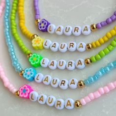 four different colored beads with name charms on them