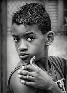 a black and white photo of a young boy with his hand on his chin looking at the camera