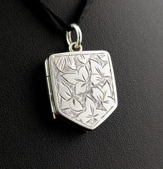 "This beautiful antique Victorian sterling silver locket pendant is so decorative and unique with its attractive nature inspired design. It is engraved to the front in the aesthetic manner with leaves and the locket is a lovely shield shape.  It has a silver jump ring and space internally for two pictures or tiny mementos but there are no glazed covers.  The locket has a smooth reverse and is marked with a makers mark.  This is perfect for adding to your favourite long chain or necklace.  Marks and era: Victorian era, marked JR, tests as sterling silver, c1880s Condition: Good used condition overall, some age commensurate wear and signs of use, light surface wear.  Approx measurements: 0.75\" width  1\" height including the bale.  Weighs approx 7.85 grams Any questions or queries please co Engraved White Gold Pendant Locket Necklace, Silver Pendant Locket Necklace, Silver Locket Pendant Necklace, Silver Pendant Locket Necklace With Engraving Option, Traditional Silver Pendant Locket Necklace, Etched Silver Pendant Locket Necklace, Etched Silver Locket Pendant Necklace, Silver Jewelry With Flower Pendant Locket, Sterling Silver White Engraved Locket Necklace