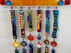 a wall hanging made out of different colored glass beads and metal chains with bead ends