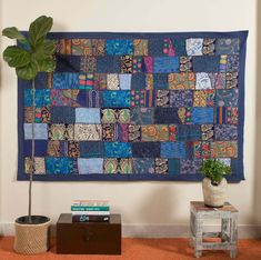 a blue patchwork wall hanging over a table with a potted plant on it