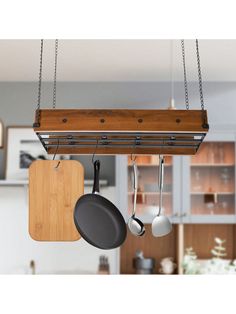 a kitchen with pots and pans hanging from the ceiling, next to a cutting board