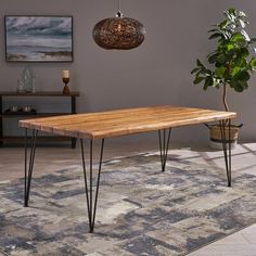 a wooden table sitting on top of a rug next to a potted green plant