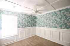 an empty room with floral wallpaper and white wainscothes on the walls