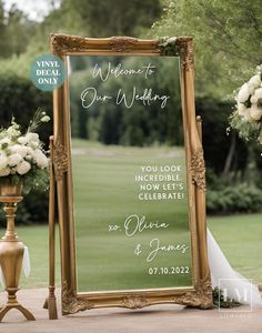 a large mirror sitting on top of a sidewalk next to a vase filled with flowers