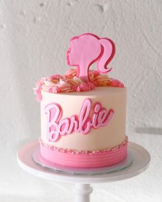 a cake with pink frosting and the word barbie on top is sitting on a plate