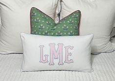 two pillows on top of a bed with the word lme in pink and green