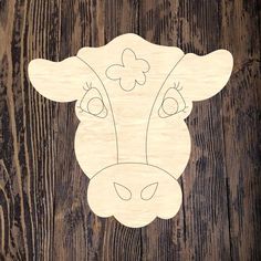 a wooden cutout of a cow's head on a wood background with flowers